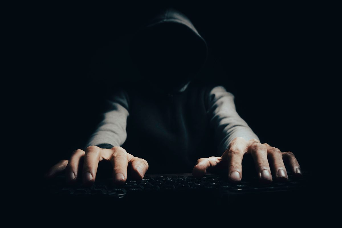 Anonym person i hoodie vid tangentbord – symbol för oseriösa aktörer i bolagsuppköp